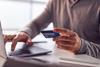 An anonymous man types in his bank card details on a laptop