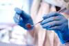 An anonymous dentist wearing gloves holds dentistry equipment